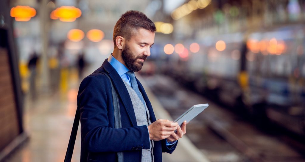 Digitalisaatio muuttaa lukemista: Mies lukee tabletiltaan juna-asemalla.